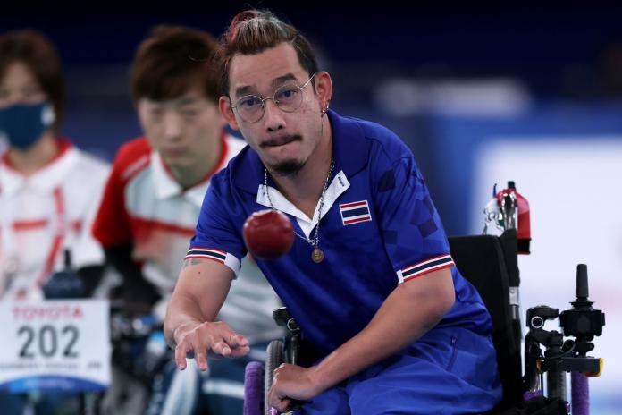 Thai boccia athlete Watcharaphon Vongsa throws a red ball during a competition.