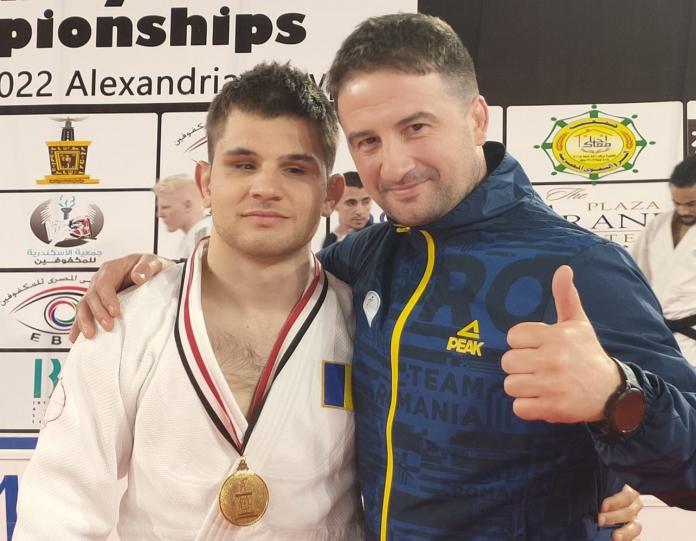 A male judoka and his coach pose for a photo.