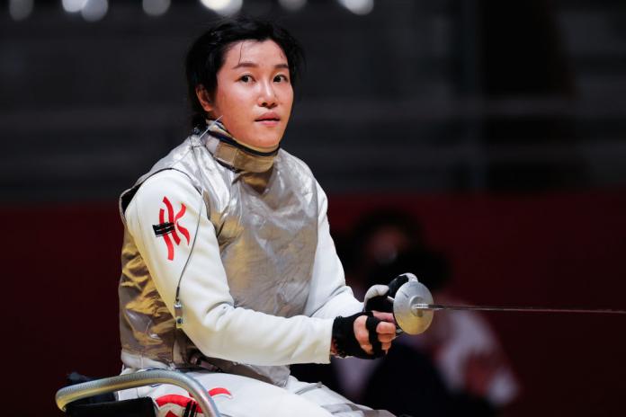 A female wheelchair fencer looks at the camera