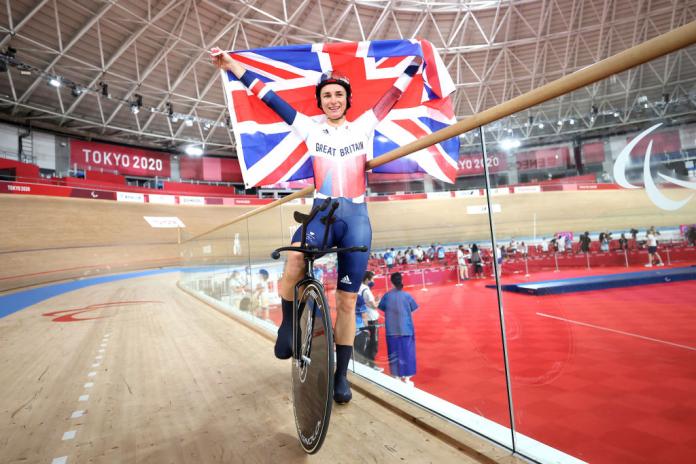 A female Para cyclist celebrates by holding the British flag