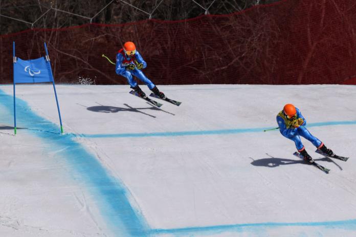 A male skier and his guide compete at Beijing 2022.