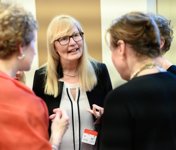 A female official engaging with two people.