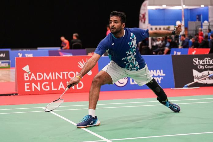 A male Para badminton athlete attempts to return the shuttle during a match