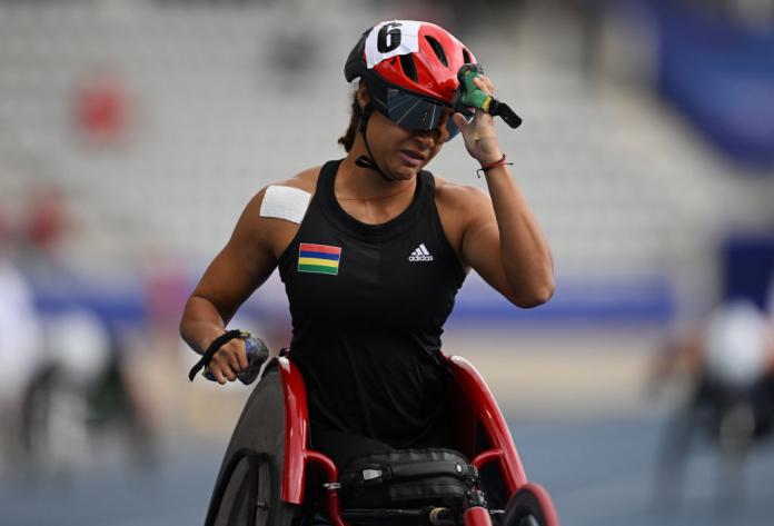 The photo shows a female wheelchair racer. She is wearing a helmet 