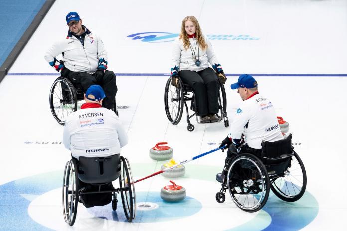 Four wheelchair curlers during a game.