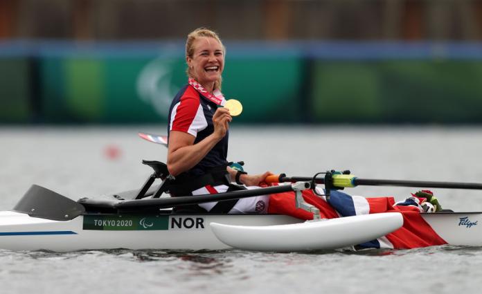 Para rower Birgit Skarstein in her boat holding her gold medal and smiling 