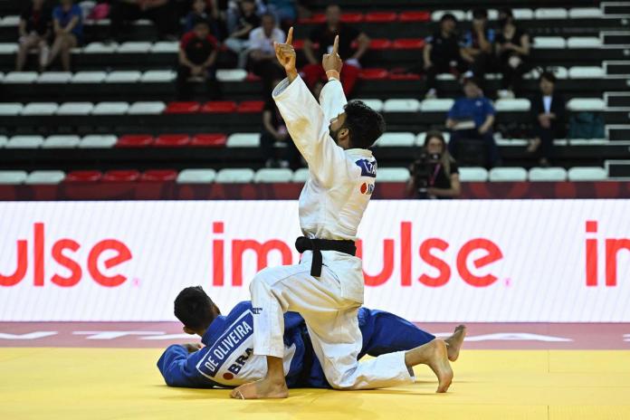 A male Para athlete celebrates on the mat after a win.
