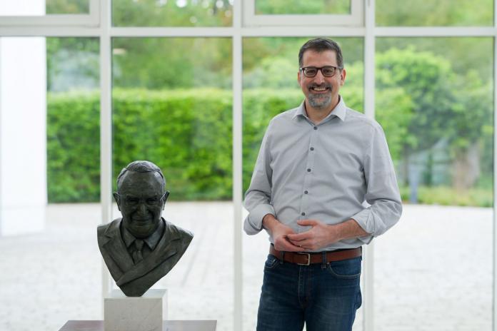 IPC CEO Mike Peters poses for a photo next to a bust statue of Sir Ludwig Guttman.