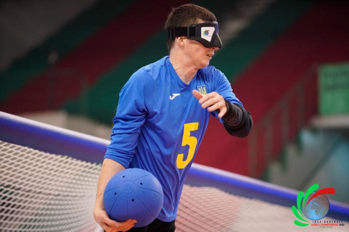 Rodion Zhyhalin of Ukraine is wearing an eyeshield and holds a blue ball with his right hand.