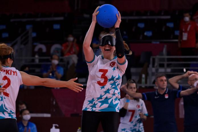 Goalball player Sevda Altonuluk holds up the ball and smiles 