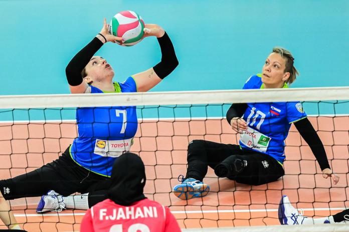 Two female sitting volleyball players compete in a Paris 2024 qualification tournament.