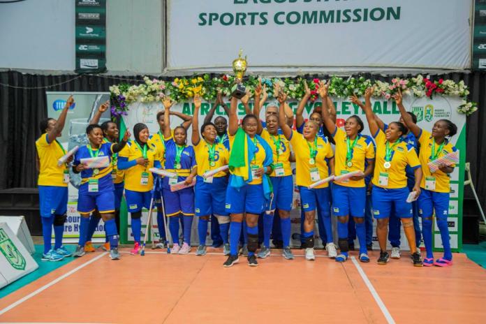 Female sitting volleyball athletes celebrating after receiving a trophy