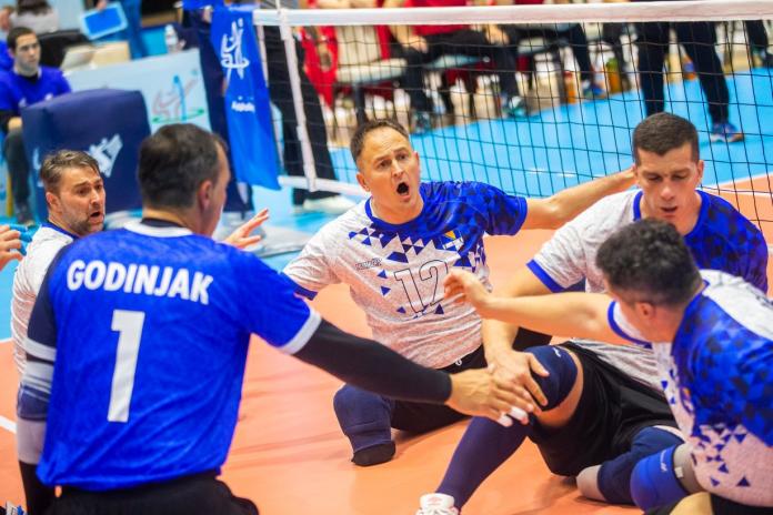 Male sitting volleyball players form a circle on court