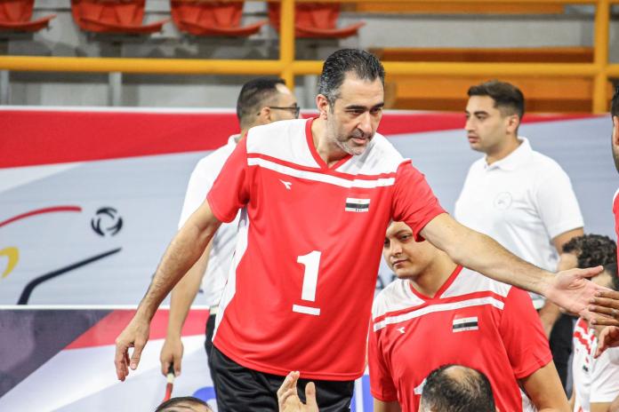 A male sitting volleyball player greets a teammate