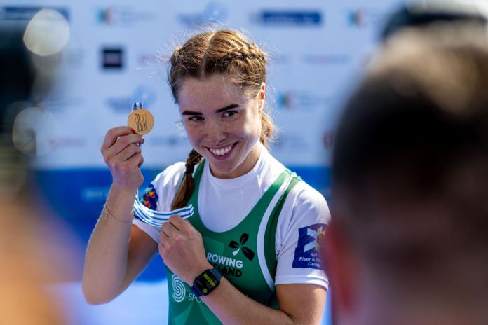 A female athlete poses for a photo with a gold medal