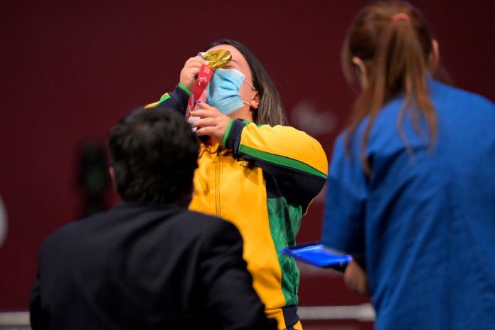 A female Para powerlifting athlete celebrates after receiving a gold medal.