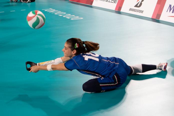 A female sitting volleyball athlete tries to return a ball