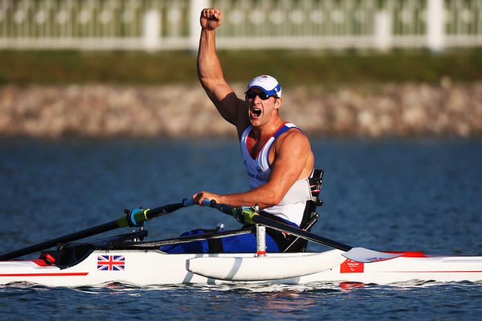 A male Para rower pumps his right fist after winning a medal at the Beijing 2008 Paralympic Games.