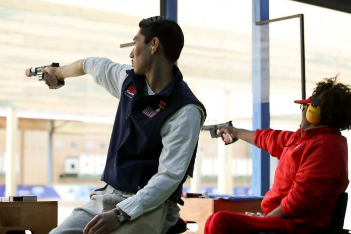 A male shooting Para sport athlete aims for a target