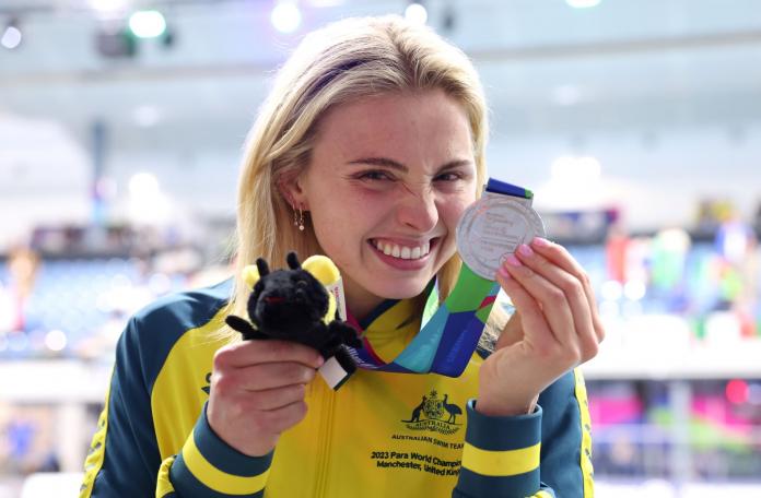 A female Para swimmer holds a silver medal in front of her face
