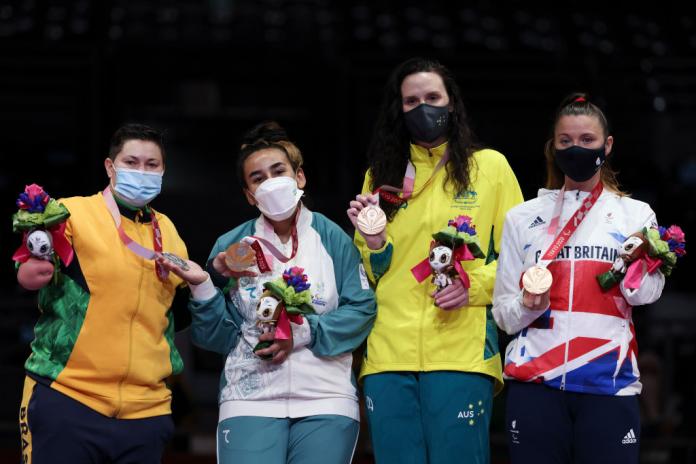Four female athletes pose for a photo with their medals 