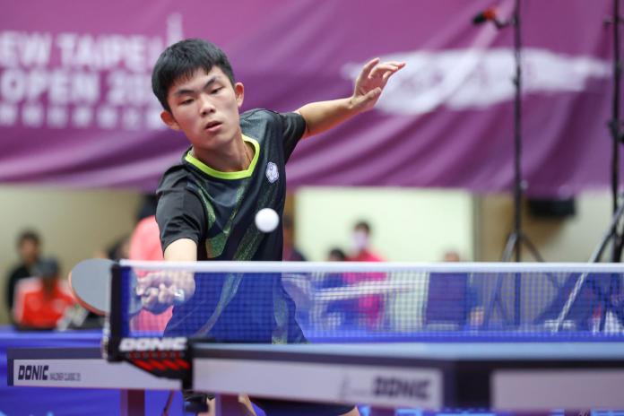 A male Para table tennis athlete reaches out to return a ball 