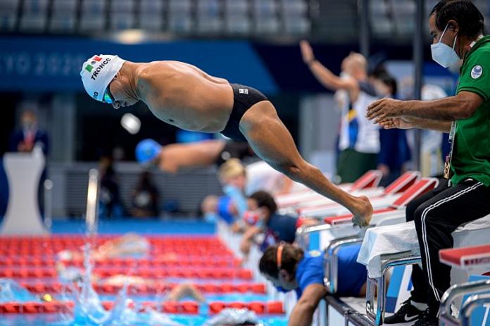 A male Para swimmer jumps into the pool