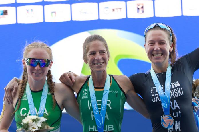 Three Para triathletes pose for a photo on the podium
