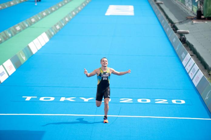 A male Para athlete makes a thumbs up as he crosses the finish line