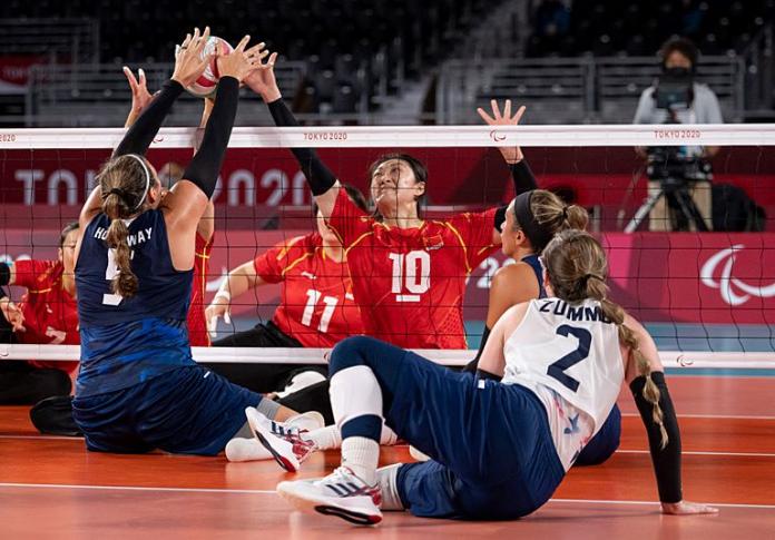 Yixiao Xu tries to get the ball over the net, while her opponent blocks.