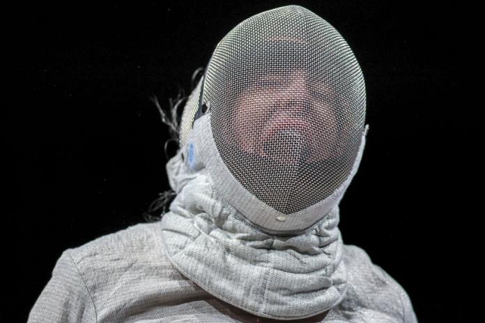 A female wheelchair fencer, who is wearing a mark, reacts