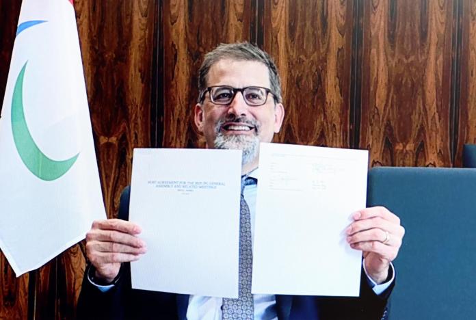 Mike Peters, the CEO of the International Paralympic Committee holds two sheets of paper. 