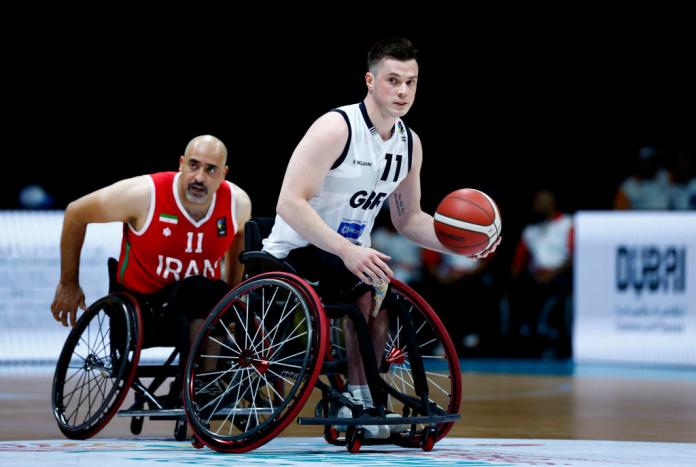 A male wheelchair basketball player controls the ball