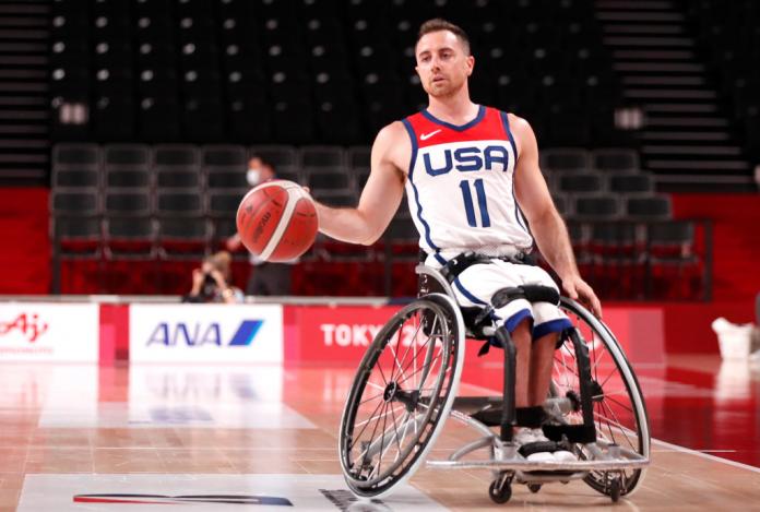 Un jugador masculino de baloncesto en silla de ruedas lleva el balón durante un partido