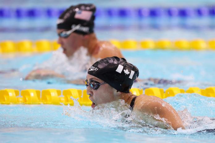 A female swimmer with another swimmer in the background in a race