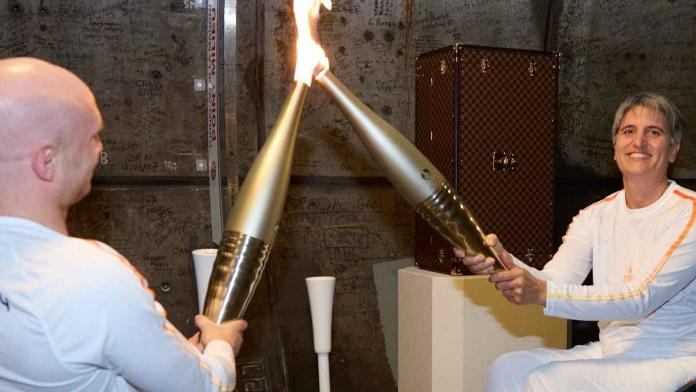 two Para athletes in wheelchairs holding together the Paralympic torch