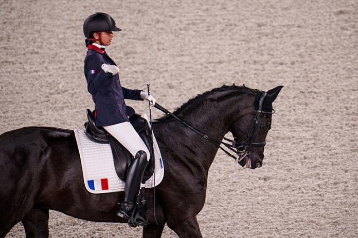 A female Para equestrian athlete rides a horse
