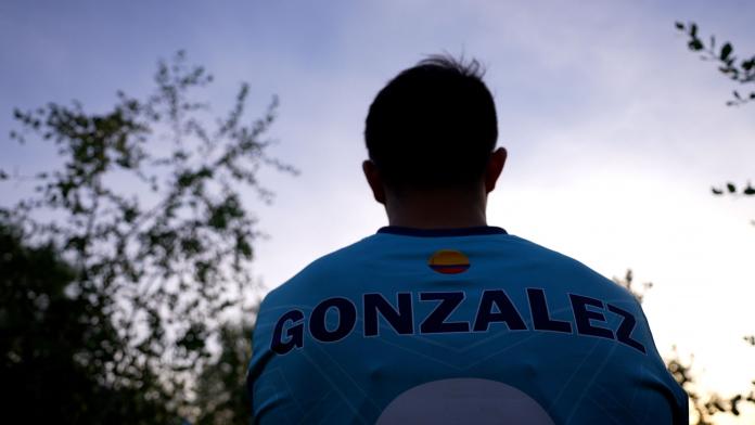 Jhon Gonzalez, a blind football player from Colombia, is standing outdoors, his back toward the camera