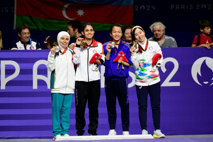 Four Para taewondo athletes smile and pose for a photo during the victory ceremony