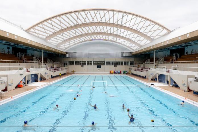 A wide shot of a pool. People are playing water polo.