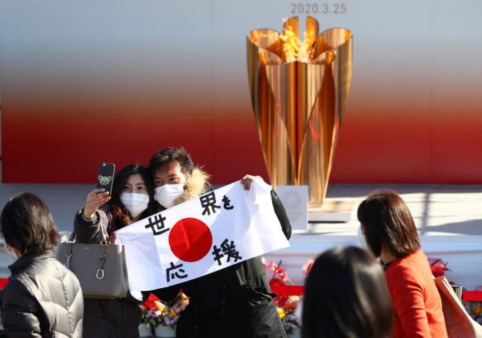 Japanese tourists take a photo in front of the Paralympic torch 