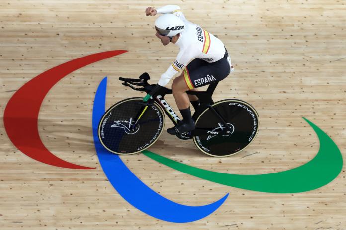 Alfonso Cabello Llamas rides his bike over the Agitos logo on the track, and raises his arm in celebration