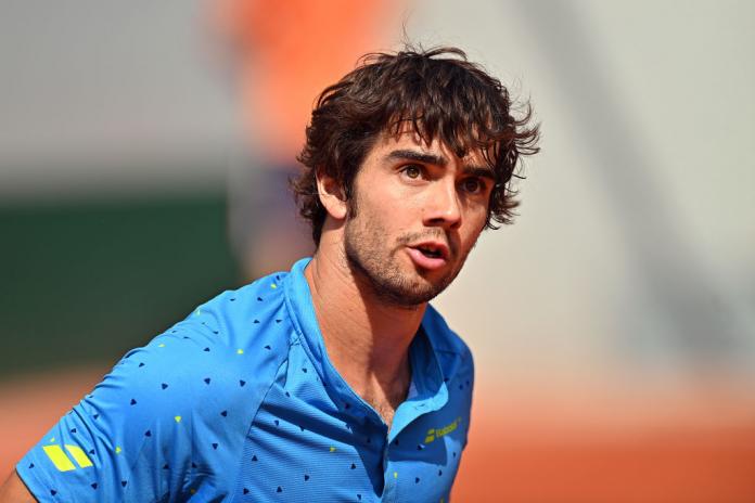 Spanish tennis player Daniel Caverzaschi, wearing a blue shirt, contemplates his previous shot