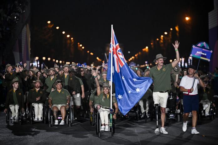 A group of Australian Para athletes parading with the national flag 