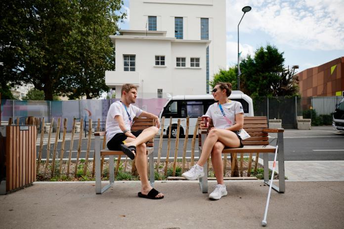 two athletes sitting on a bench chatting 