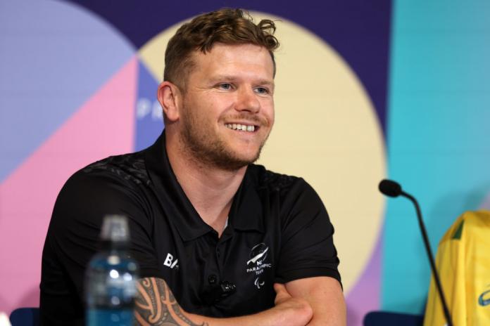 Para swimmer Cameron Leslie smiling behind a microphone