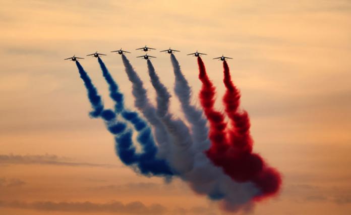 A group of planes flying in formation displaying coloured smoke
