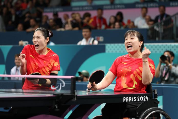 Liu Jing and Xue Juan yell in celebration during a Para table tennis match