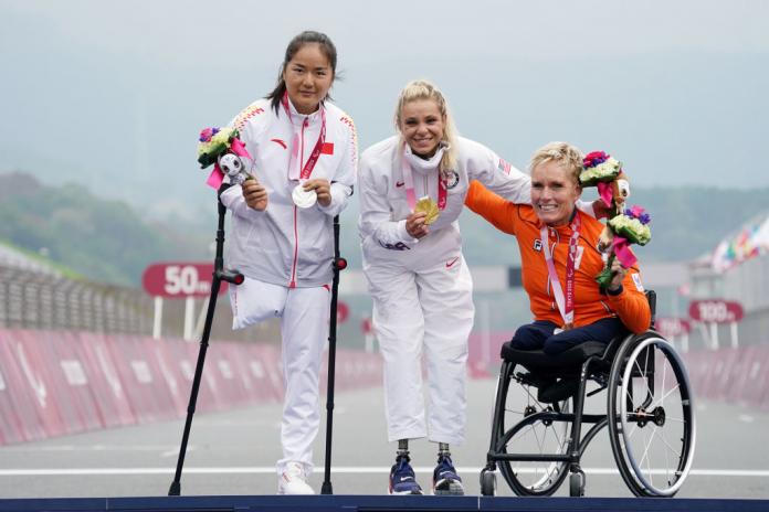 A female athlete wearing an orange uniform competes in handcycling