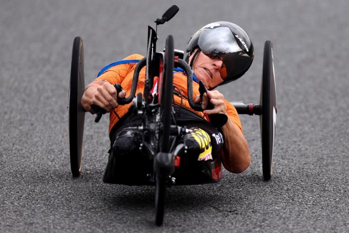 A female athlete wearing an orange uniform competes in handcycling